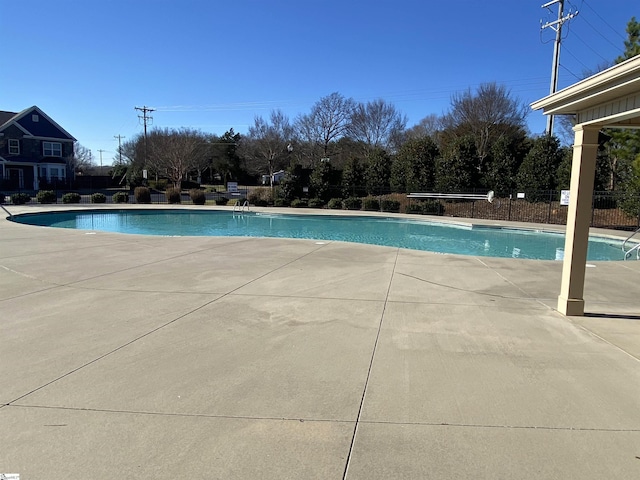 community pool with a patio area and fence