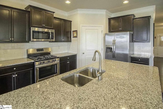 kitchen with a sink, ornamental molding, light stone counters, and stainless steel appliances