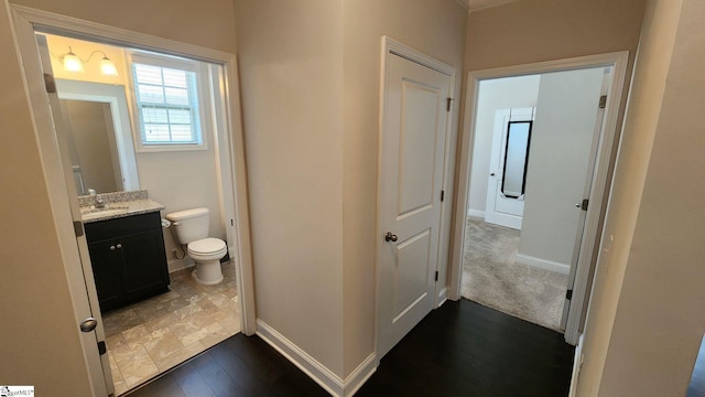 bathroom with baseboards, toilet, wood finished floors, and vanity