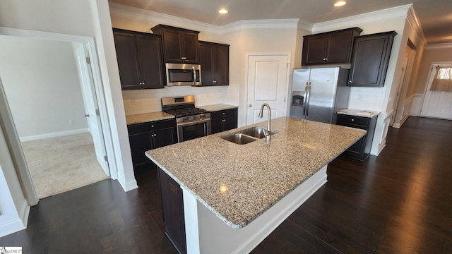 kitchen with a sink, stainless steel appliances, a kitchen island with sink, and dark wood-style flooring