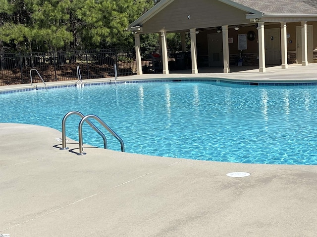community pool with a patio, fence, and ceiling fan