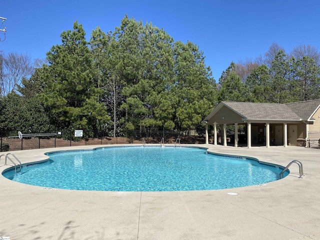 pool with a patio area and fence