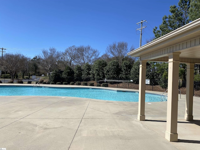 pool with a patio area and fence