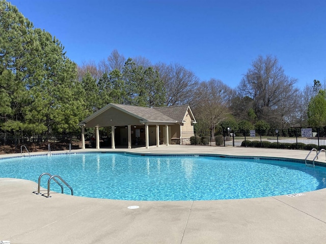 community pool with a patio area and fence