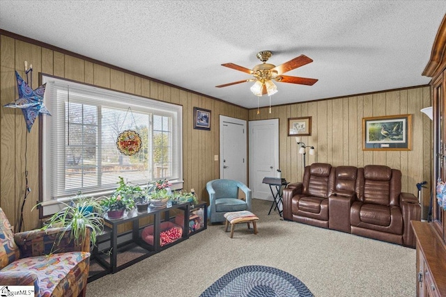 living area featuring wooden walls, ceiling fan, crown molding, a textured ceiling, and carpet flooring