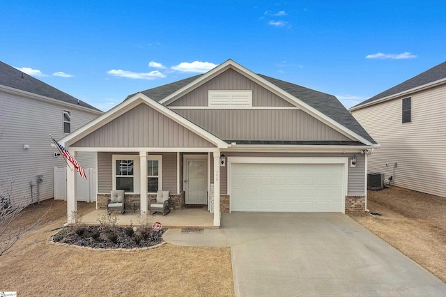 craftsman inspired home with a porch, driveway, an attached garage, and central AC unit