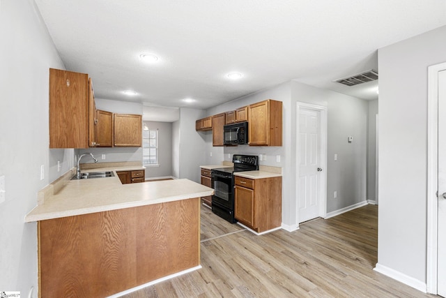 kitchen featuring visible vents, brown cabinetry, light countertops, black appliances, and a sink