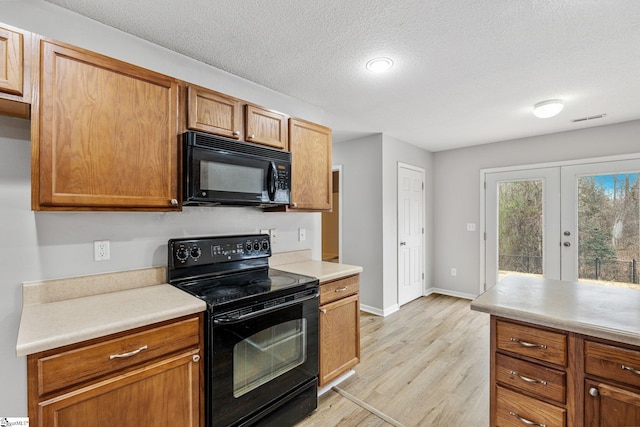 kitchen featuring black appliances, french doors, light countertops, and light wood-style floors