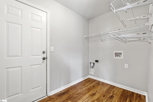 clothes washing area featuring a textured ceiling, laundry area, dark wood-style flooring, washer hookup, and baseboards