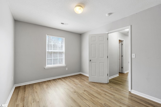 unfurnished bedroom with baseboards, a textured ceiling, visible vents, and light wood-style floors