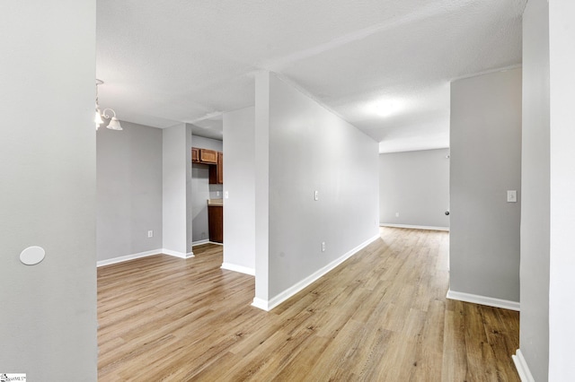 unfurnished room featuring a textured ceiling, light wood-style flooring, and baseboards