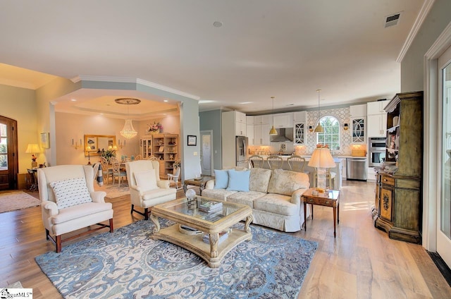 living room featuring ornamental molding, light wood-type flooring, and visible vents