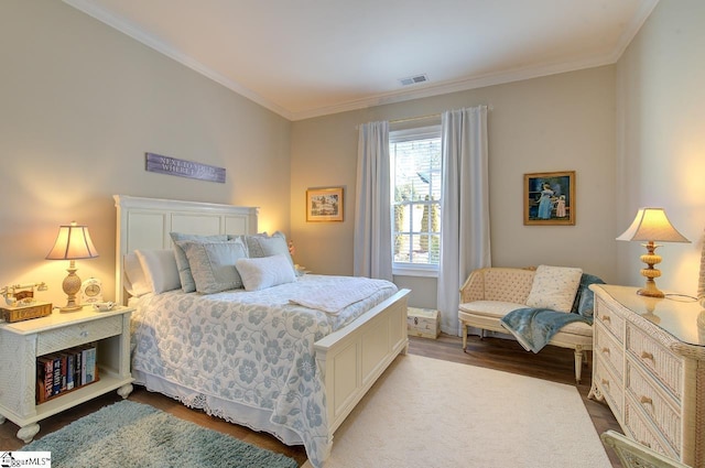 bedroom with visible vents, crown molding, and wood finished floors