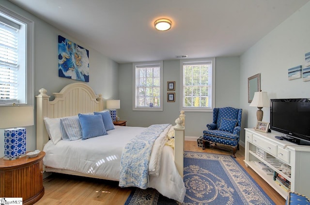 bedroom featuring wood finished floors, visible vents, and baseboards