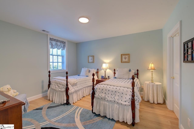 bedroom featuring visible vents, light wood-style flooring, and baseboards