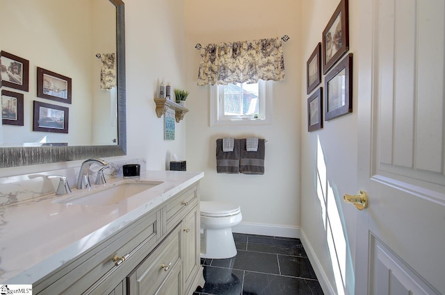 half bathroom featuring baseboards, vanity, and toilet