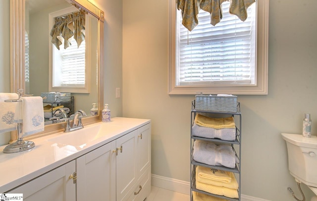 half bath with toilet, plenty of natural light, vanity, and baseboards