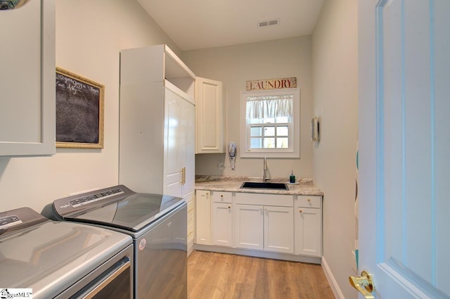 laundry area with cabinet space, visible vents, light wood-style flooring, a sink, and separate washer and dryer