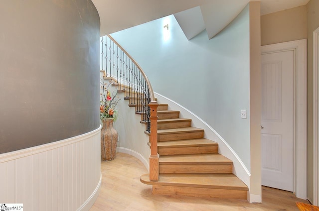 staircase featuring wood finished floors and wainscoting