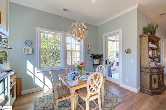 dining space featuring wood finished floors, visible vents, crown molding, and an inviting chandelier