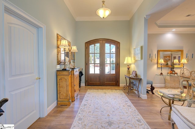 entrance foyer featuring visible vents, arched walkways, crown molding, french doors, and light wood-style floors