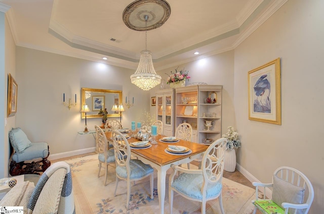 dining space featuring baseboards, visible vents, a tray ceiling, crown molding, and a notable chandelier