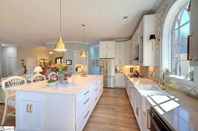 kitchen with a breakfast bar area, stainless steel appliances, a sink, white cabinets, and tasteful backsplash