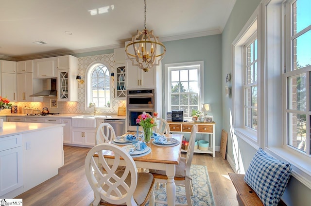 dining space with light wood finished floors, visible vents, baseboards, crown molding, and a notable chandelier