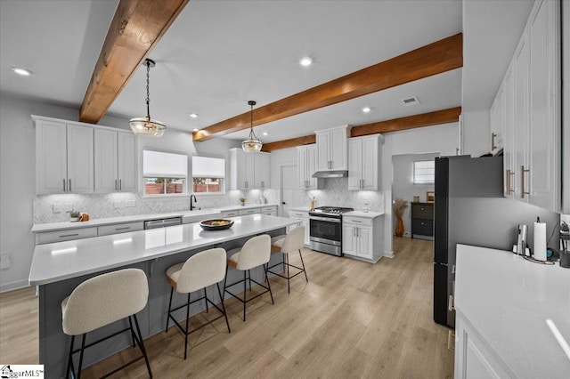 kitchen with a healthy amount of sunlight, a breakfast bar, white cabinets, and stainless steel appliances