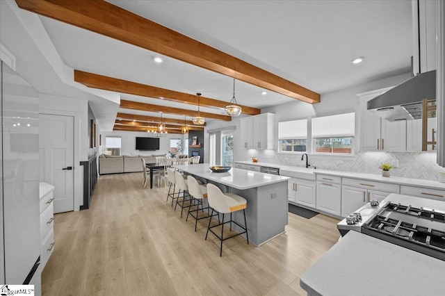 kitchen featuring tasteful backsplash, a kitchen island, a breakfast bar, extractor fan, and white cabinetry