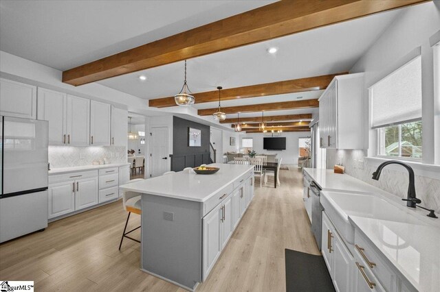 kitchen featuring freestanding refrigerator, a center island, white cabinets, and light wood-style flooring