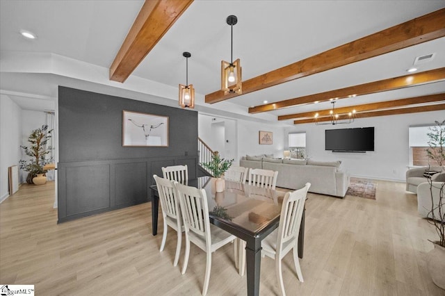 dining area featuring light wood-type flooring, stairs, visible vents, and beam ceiling