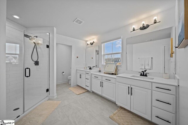 full bath featuring double vanity, visible vents, toilet, a shower stall, and a sink