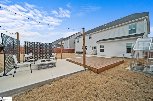 rear view of property featuring a patio area, fence, a fire pit, and a deck