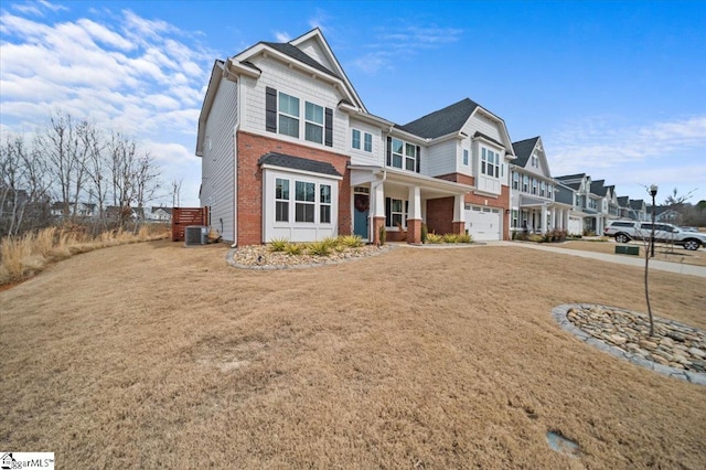 view of front facade with a garage, driveway, a residential view, central AC, and brick siding