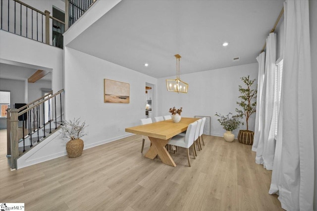 dining room with a notable chandelier, stairway, light wood-type flooring, and baseboards