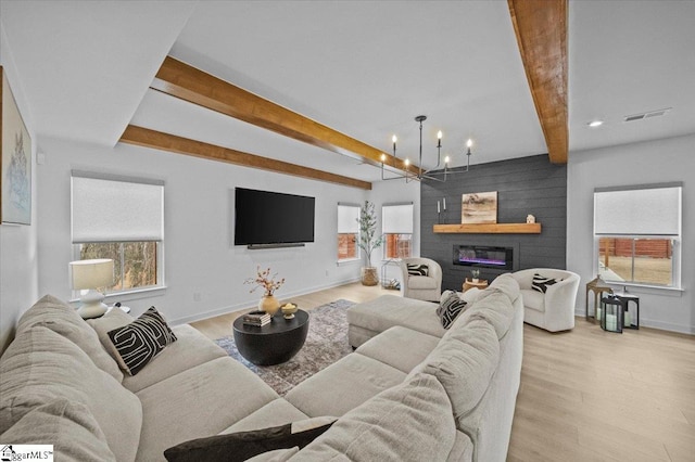 living room with a large fireplace, light wood finished floors, baseboards, visible vents, and beam ceiling