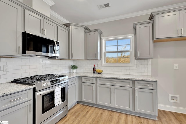 kitchen featuring visible vents, appliances with stainless steel finishes, ornamental molding, gray cabinetry, and light wood-type flooring