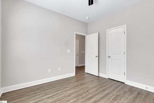 unfurnished bedroom featuring a ceiling fan, baseboards, and wood finished floors