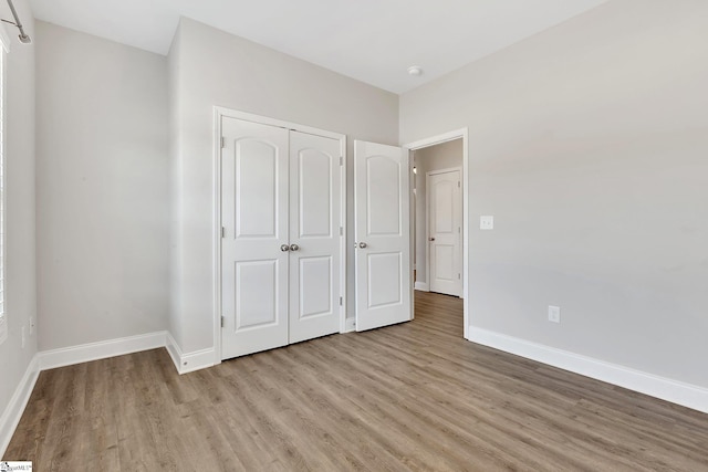 unfurnished bedroom with light wood-style floors, baseboards, and a closet