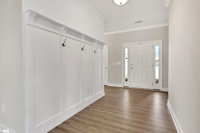 entryway featuring baseboards, wood finished floors, visible vents, and crown molding