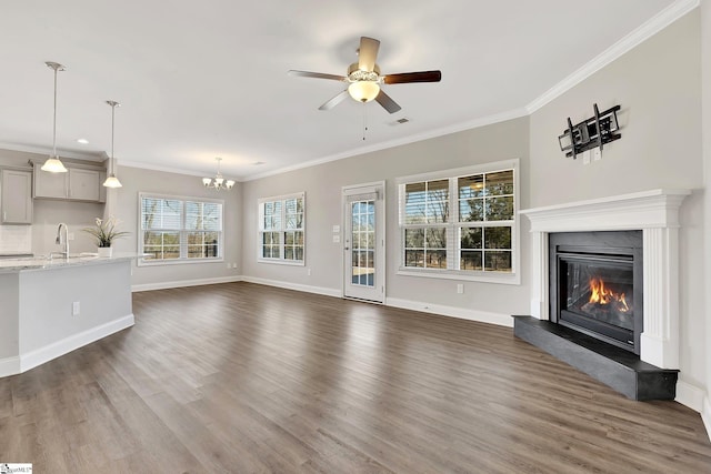 unfurnished living room featuring dark wood-style floors, visible vents, a sink, and a glass covered fireplace