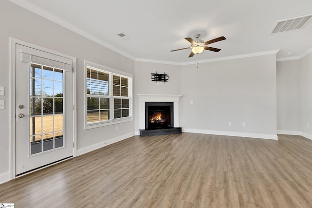 unfurnished living room featuring a warm lit fireplace, wood finished floors, visible vents, and crown molding