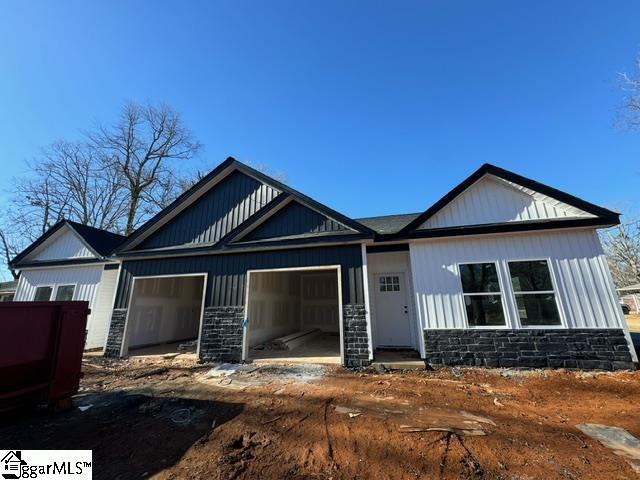 view of front of property featuring an attached garage, stone siding, and driveway