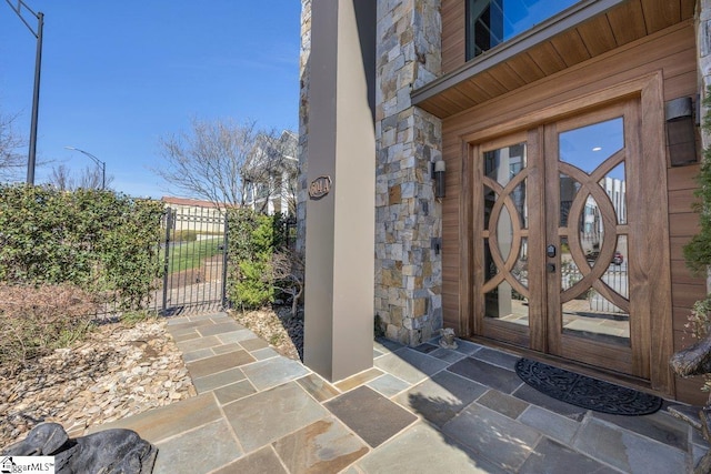 entrance to property featuring stone siding and fence