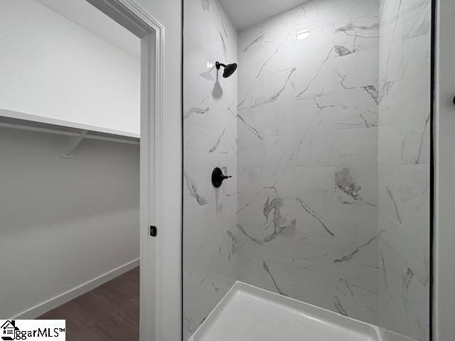 bathroom with baseboards, a marble finish shower, and wood finished floors