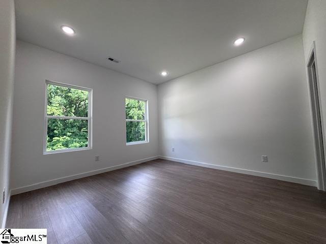 empty room with recessed lighting, baseboards, dark wood-style flooring, and visible vents