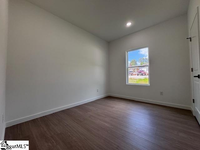 unfurnished room featuring baseboards and dark wood-style flooring
