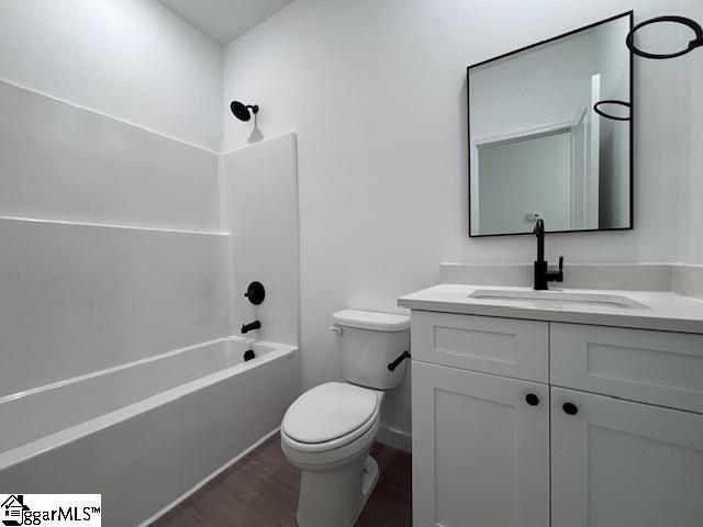 bathroom featuring vanity, wood finished floors, toilet, baseboards, and  shower combination