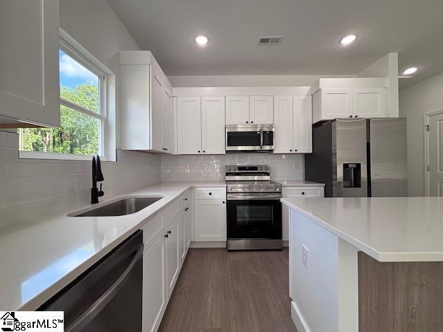 kitchen featuring a sink, appliances with stainless steel finishes, backsplash, and visible vents